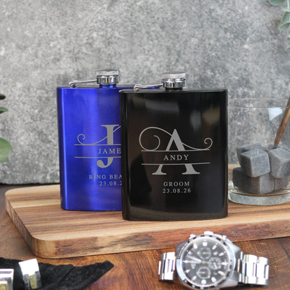 Two personalized flasks, one blue and one black, on a wooden surface with a watch in the foreground.