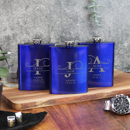 Three blue flasks with engraved names on a wooden surface with a watch and cufflinks.