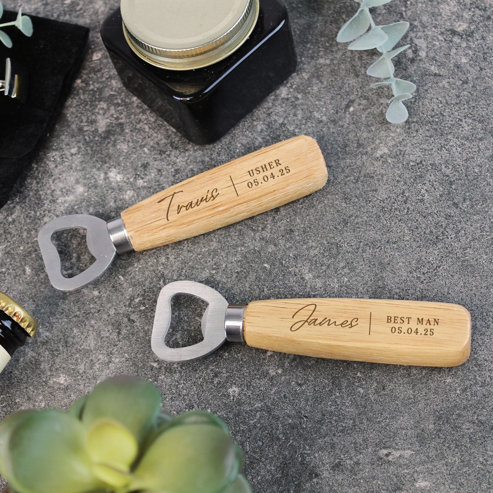 Two wooden bottle openers with engraved names on a gray surface.