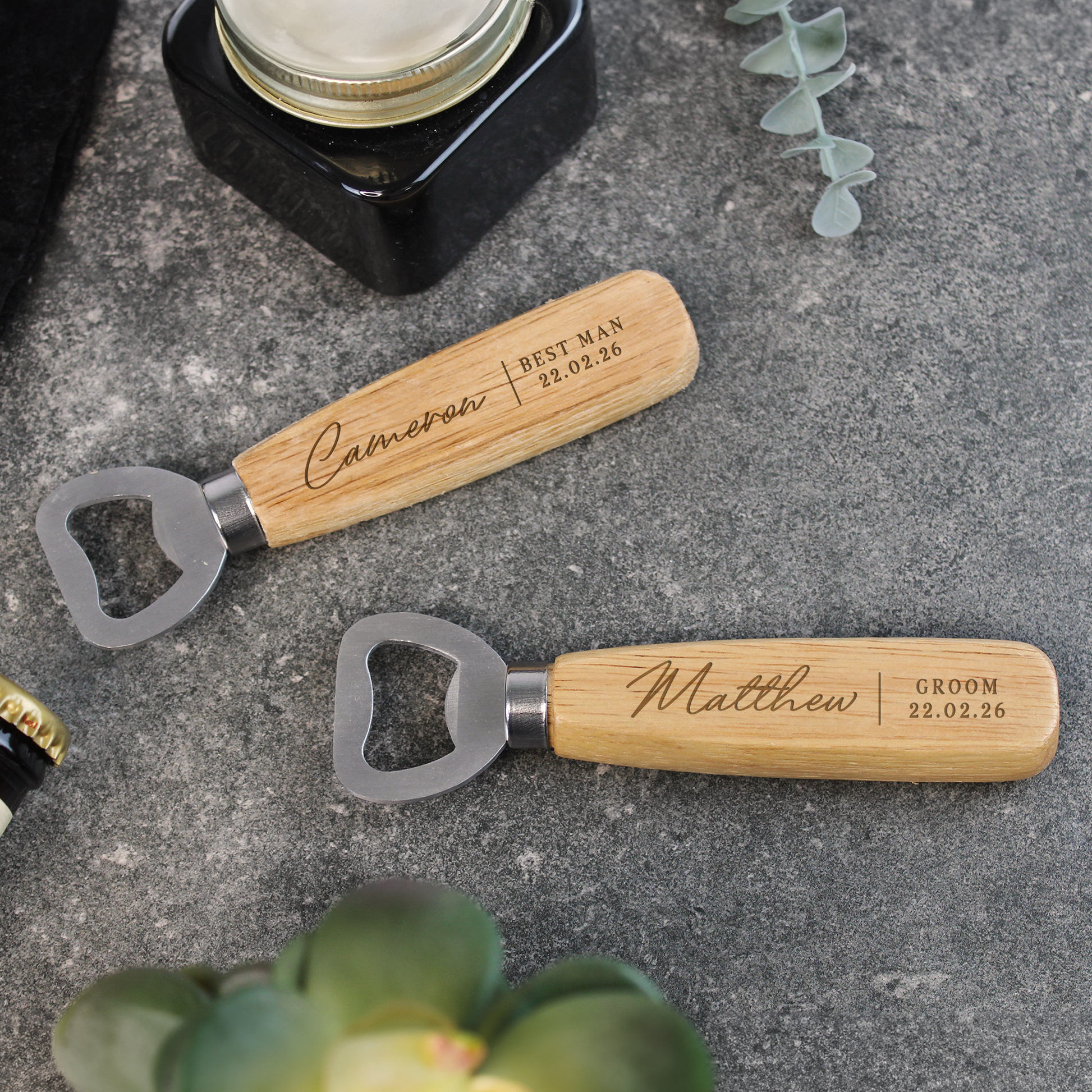 Two wooden bottle openers with engraved names on a gray surface.