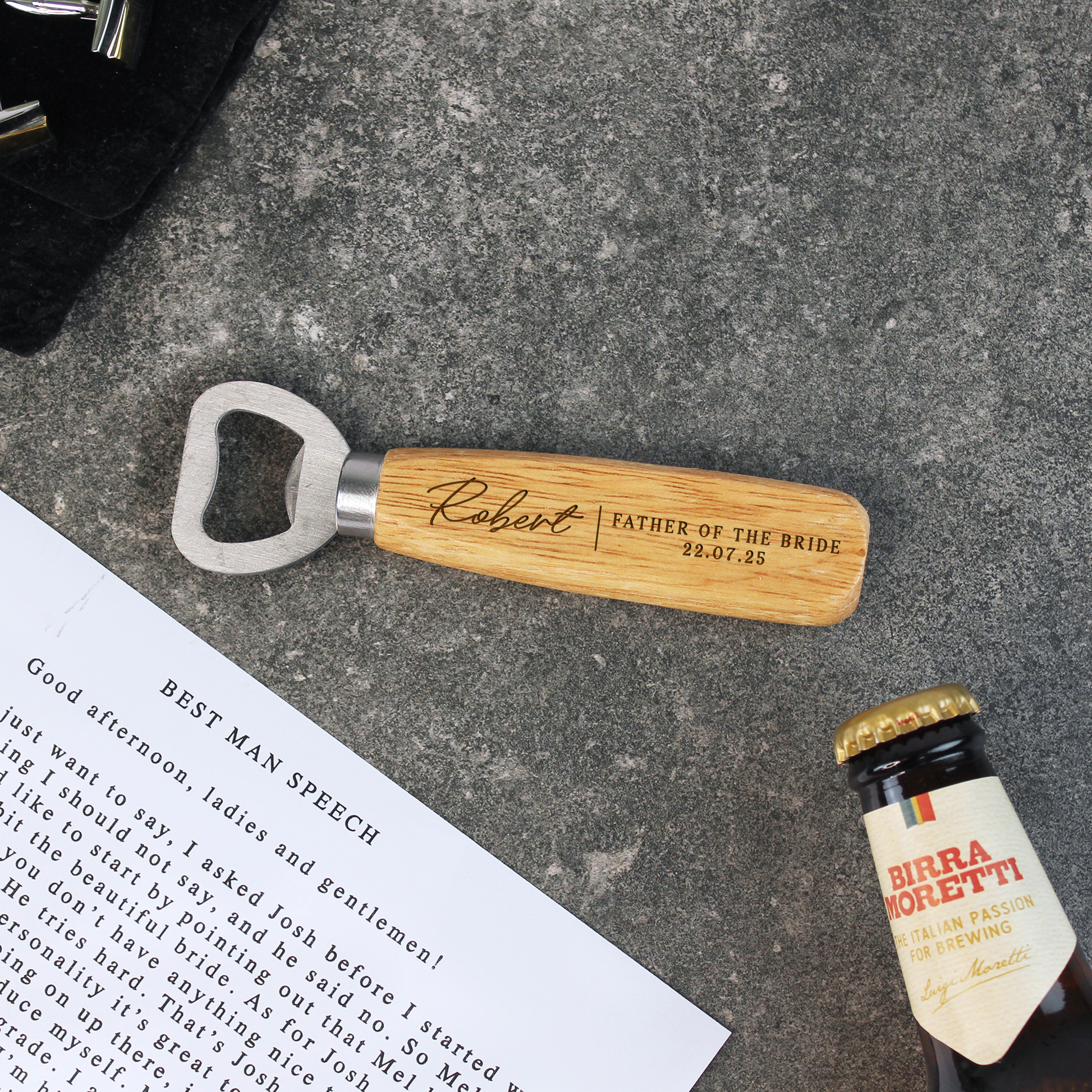 Personalized bottle opener with engraved text on a concrete surface next to a bottle of Birra Moretti.