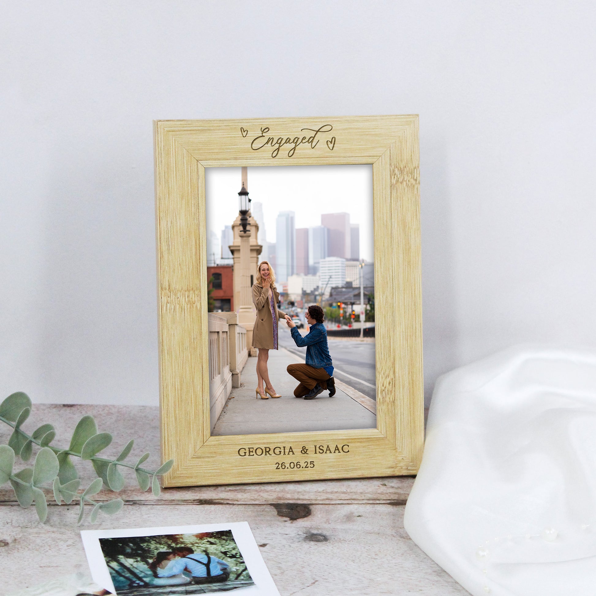 Wooden photo frame with an engaged couple picture on a light gray surface.