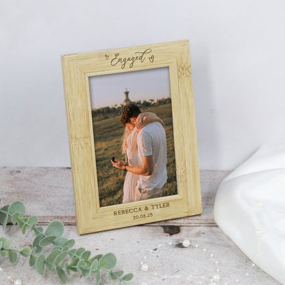 Wooden photo frame with engraved text and a couple's picture inside, on a light wooden surface.