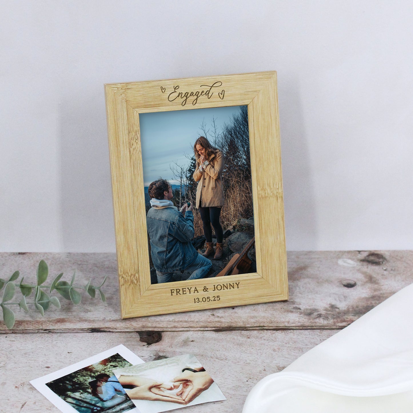 Wooden photo frame with 'Engaged' text, displaying a couple, on a wooden surface.