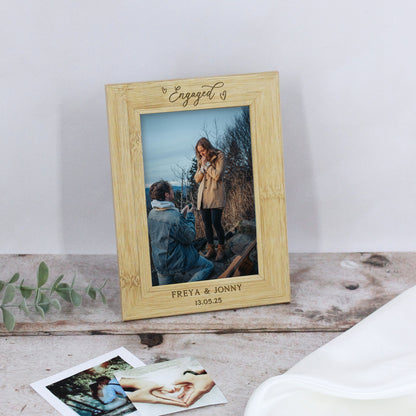 Wooden photo frame with 'Engaged' text, displaying a couple, on a wooden surface.