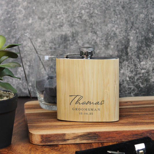Wooden flask with engraved text on a wooden surface with a plant and vase in the background